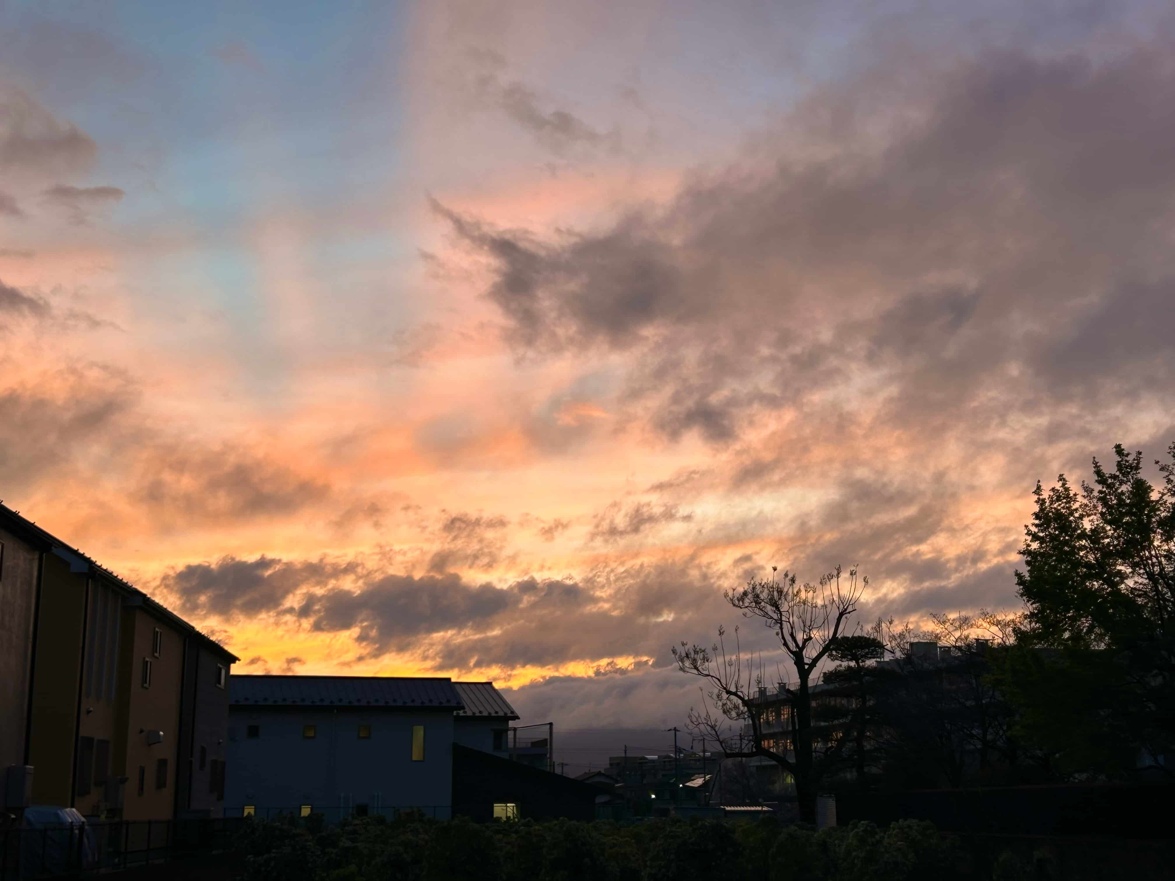 家々の上に広がるオレンジとピンクのグラデーションの夕焼け